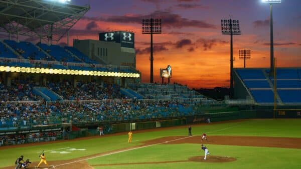 A vibrant baseball match in progress under stunning sunset skies in a crowded stadium.